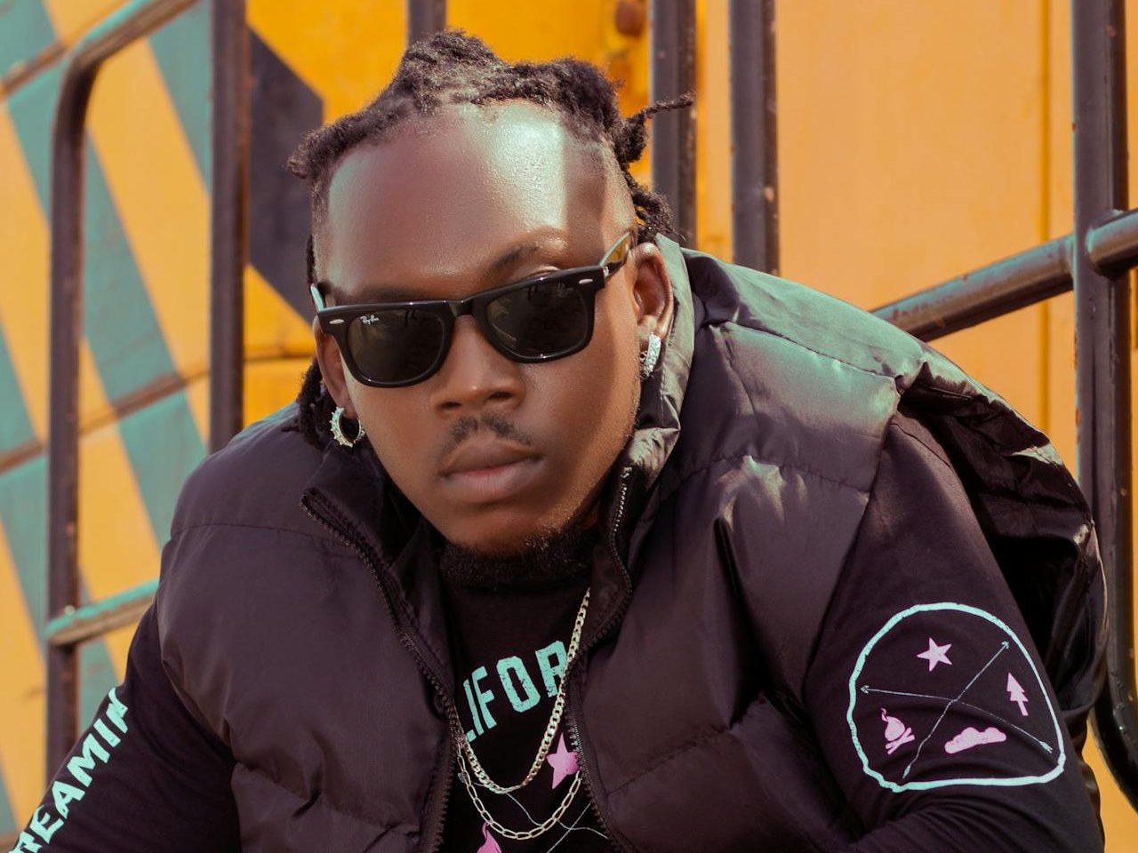 Stylish man in urban streetwear with sunglasses posing outdoors for fashion vibes.